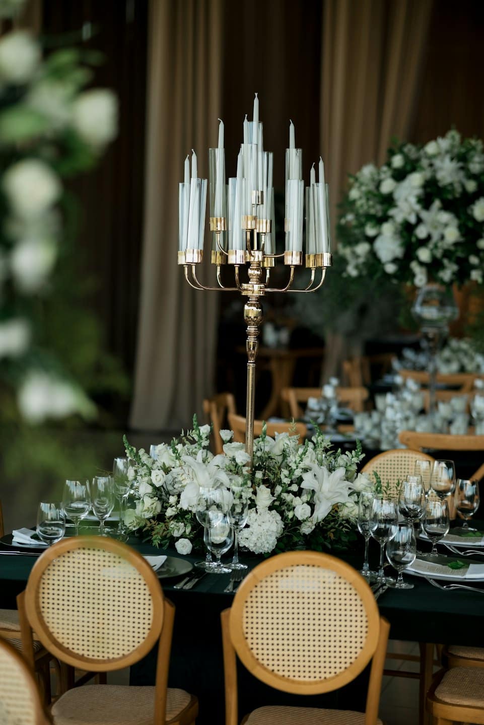 Candelabro dorado ornamentado y centro de mesa floral sobre una mesa de comedor formal.