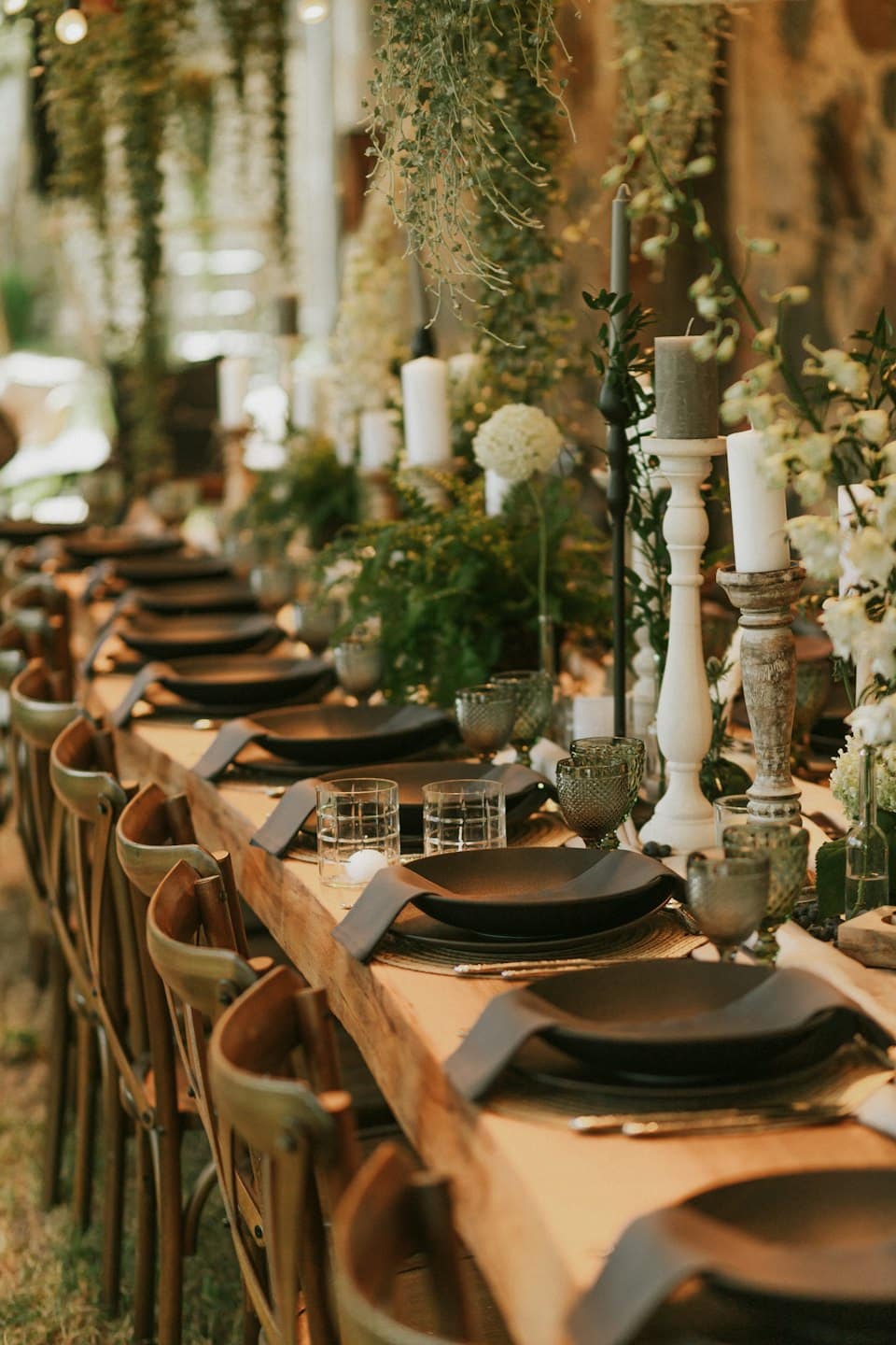 Mesa rústica de madera preparada para un evento con velas y flores.